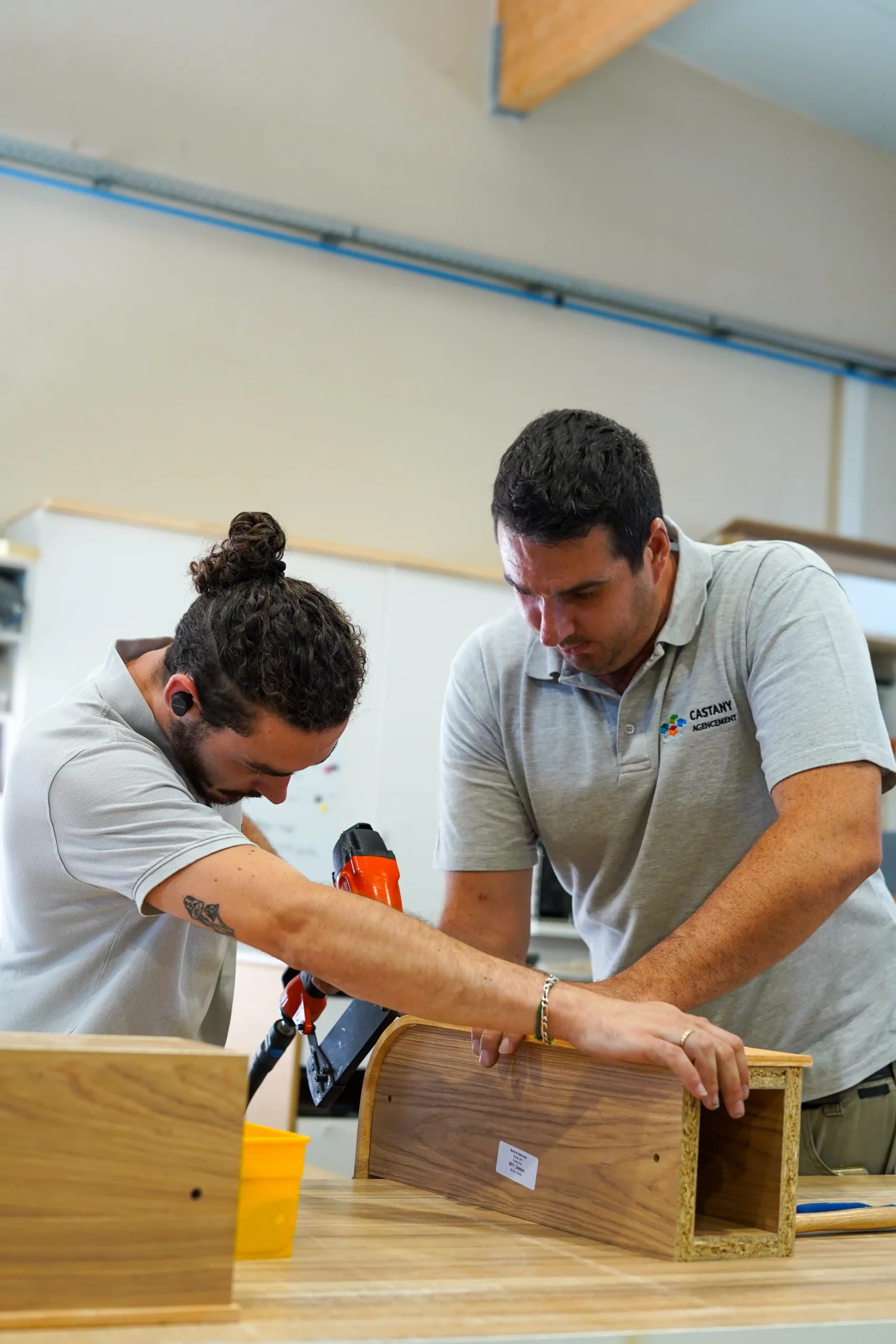Fabrication d'un mobilier sur mesure dans l'atelier de Castany Agencement par deux menuisiers agenceurs spécialisés en agencement professionnel.