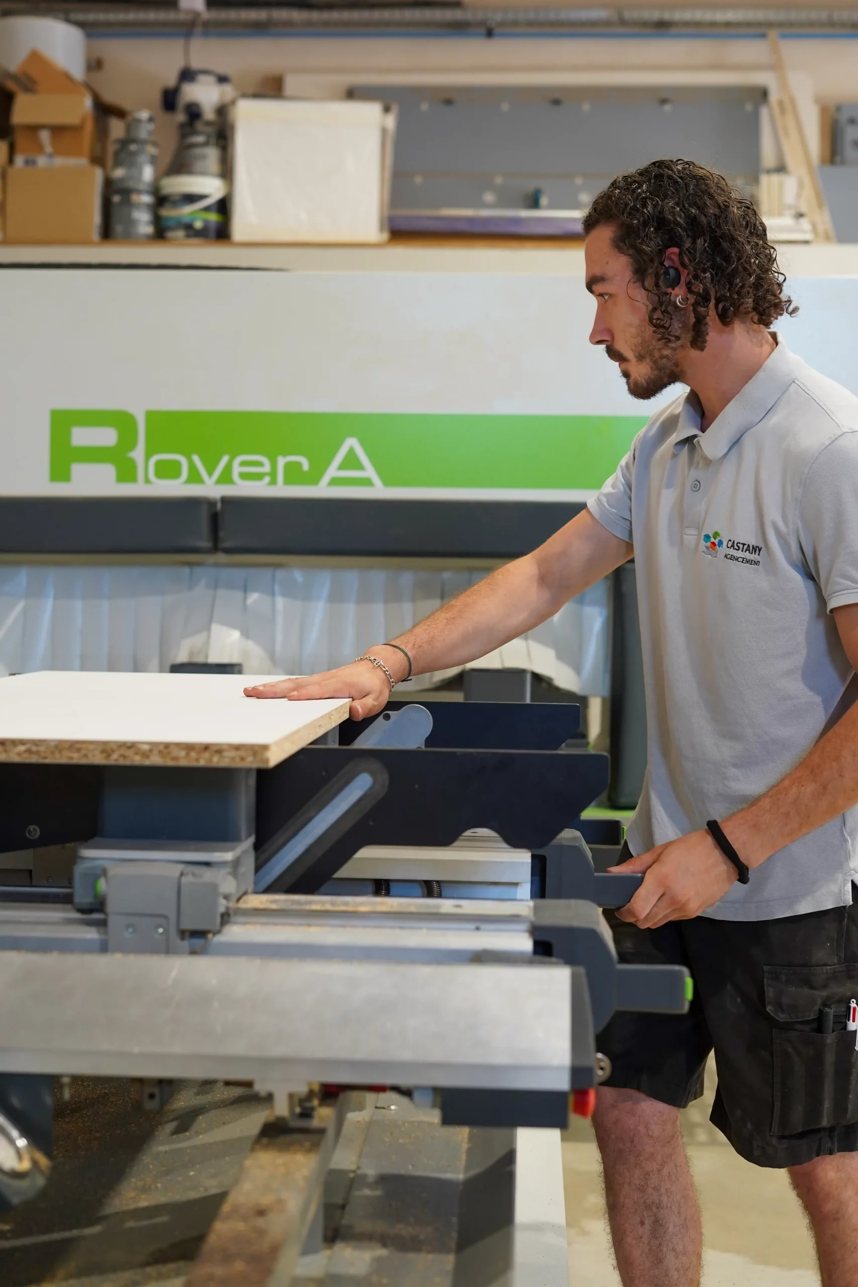 Opérateur Castany Agencement usinant un panneau de bois sur une machine à commande numérique dans l'atelier de fabrication.