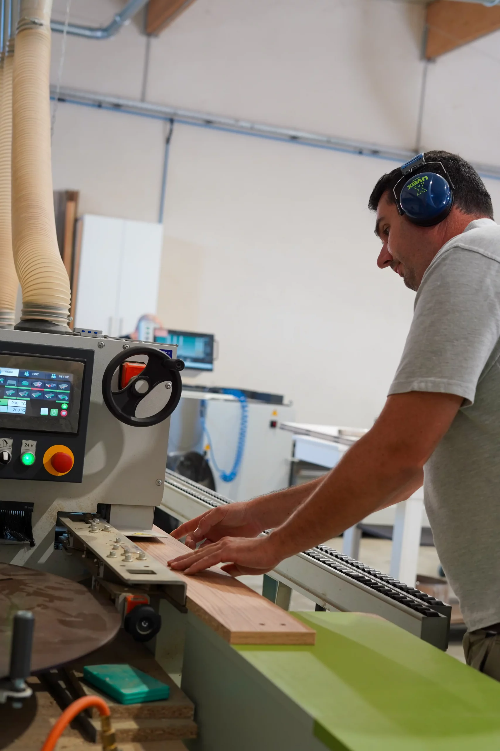 Artisan Castany Agencement usinant un panneau de mobilier sur mesure dans l'atelier de fabrication pour un projet d'agencement professionnel.