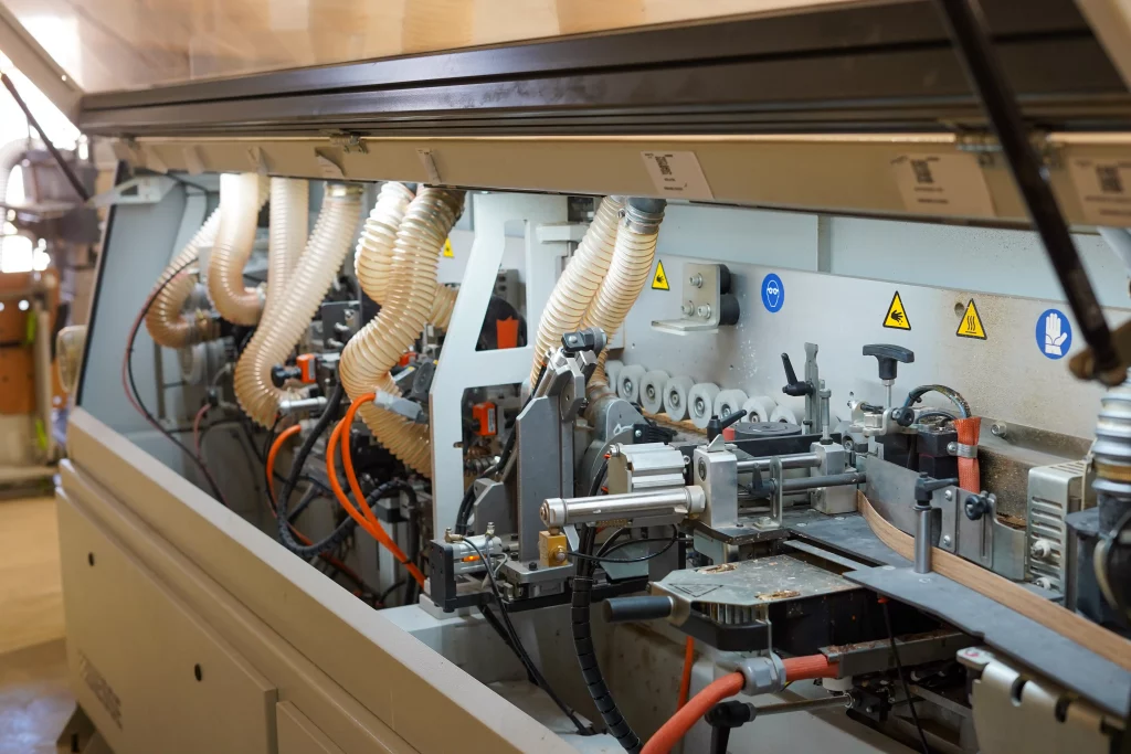 Plaqueuse de chants utilisée dans l'atelier de fabrication de Castany Agencement pour la réalisation de mobilier sur mesure.